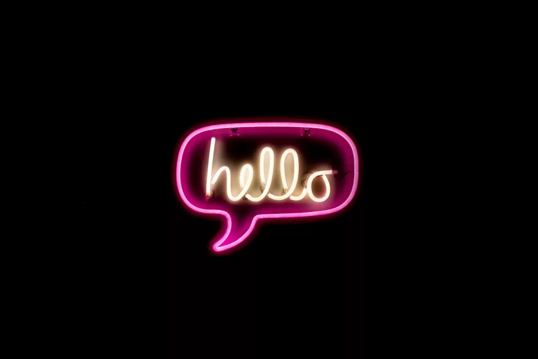 A neon sign shaped like a speech bubble with the word "hello" in cursive, glowing in pink and yellow against a black background—perfect for adding Glamesia flair to your lifestyle or fashion-inspired space.