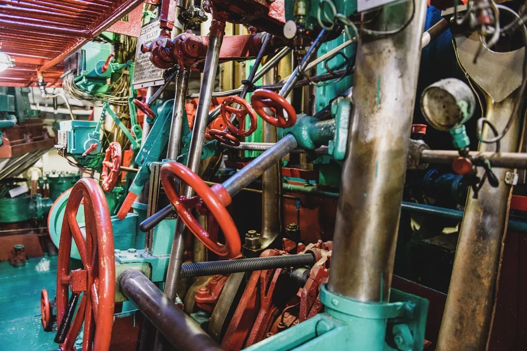 A close-up view of a ship's engine room featuring red valve wheels, pipes, gauges, and metal components—where industrial design meets the Glamesia luxury lifestyle.