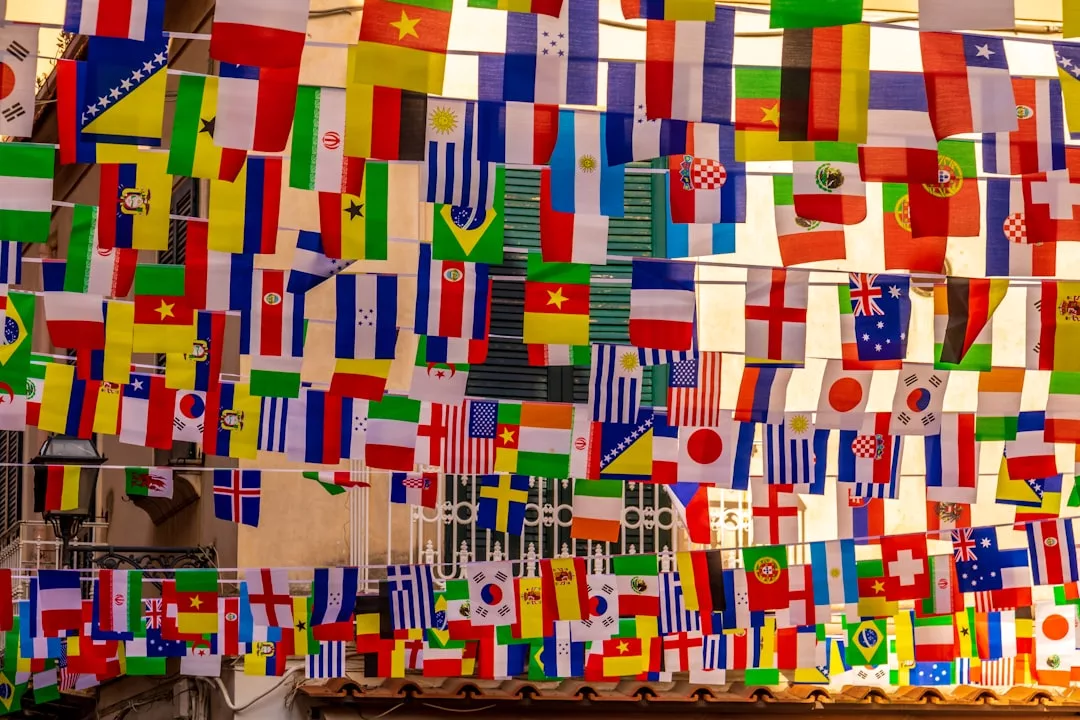 Dozens of international flags hang closely together, suspended above a street, bringing a touch of global fashion and lifestyle to the vibrant city scene.