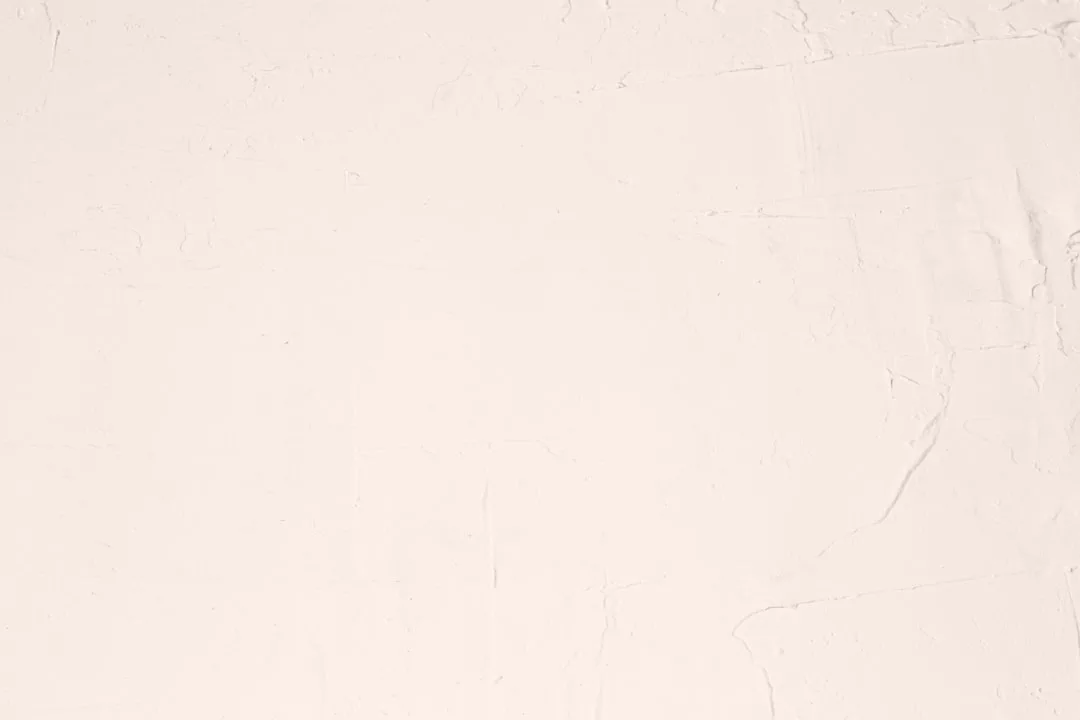 Light beige plaster wall with subtle textured patterns and faint cracks, adding a touch of Glamesia-inspired luxury to the surface.