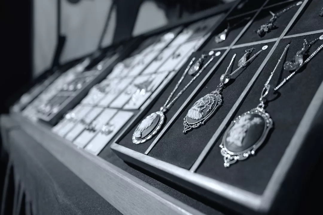 A display case containing various necklaces and jewelry, including several ornate cameo pendants, arranged in rows—a true showcase of Glamesia fashion and lifestyle elegance.