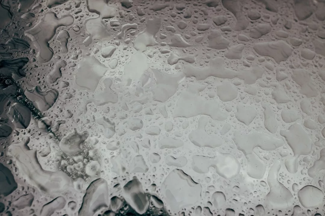 Close-up view of water droplets on a smooth, gray surface, creating various shapes and patterns that evoke an essence of luxury.