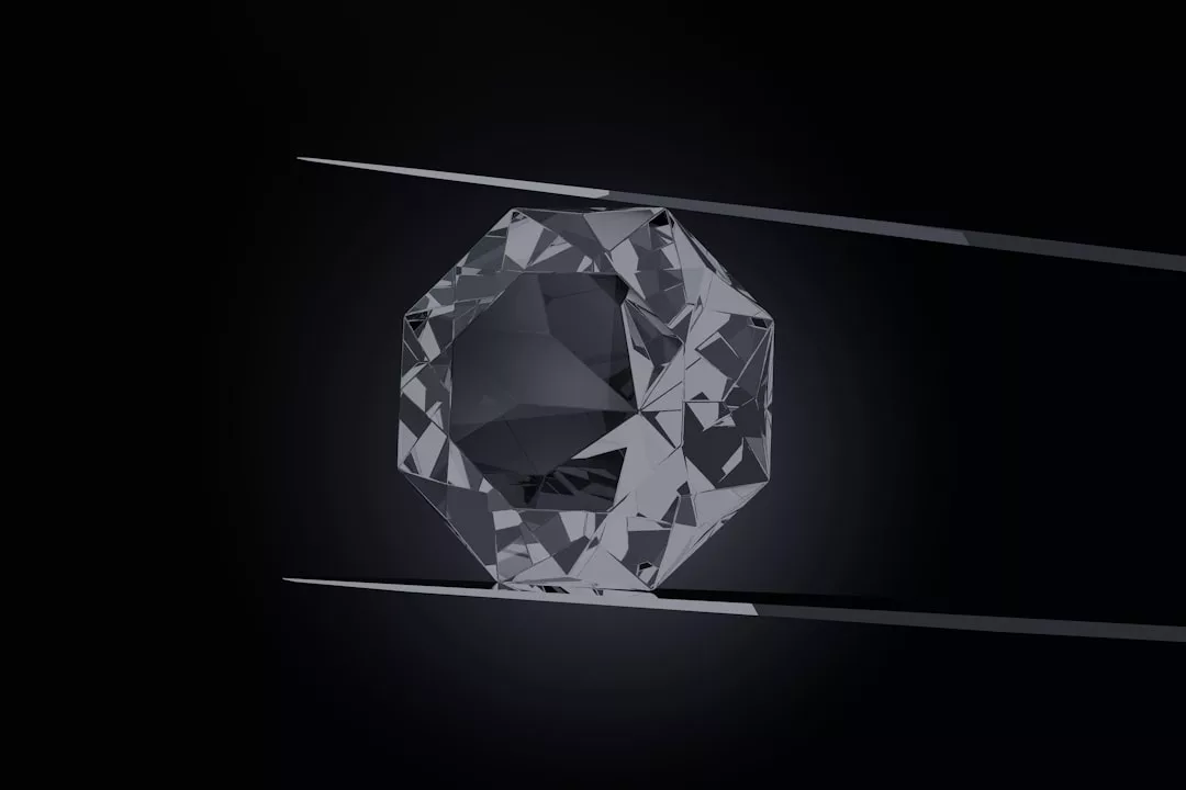 A faceted, octagonal gemstone exuding Glamesia luxury is held between two metal tweezers against a dark background.