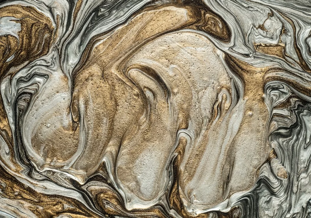Abstract pattern of swirling metallic gold, silver, and beige colors evokes a sense of Glamesia luxury, resembling marbled paint or liquid metal textures—perfect for adding a touch of fashion-inspired glam to any space.