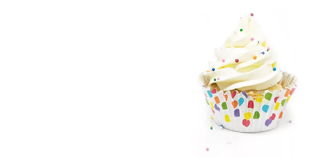 A vanilla cupcake with white frosting and colorful sprinkles in a decorative wrapper, styled to bring a touch of luxury to your lifestyle, placed elegantly on a white background.